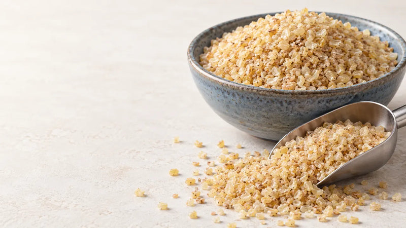 A stoneware bowl and a scoop of coarse bulgur.