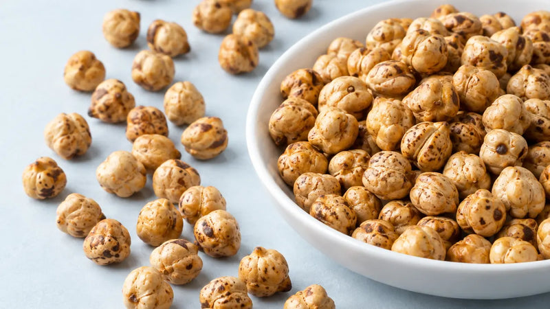 Roasted chickpeas in a white bowl on a pale blue surface.